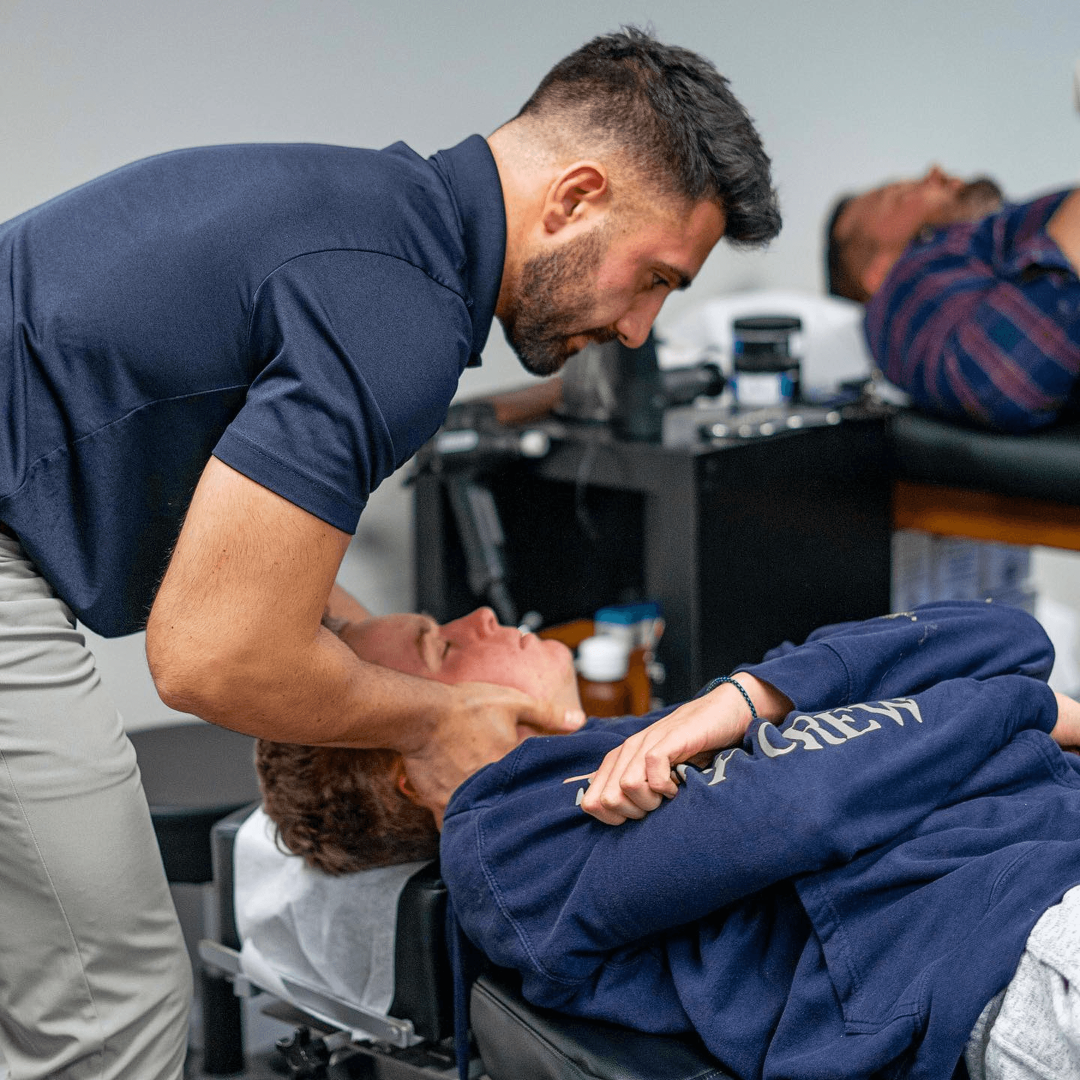 Chiropractor adjusting the neck of a patient lying face up on a treatment table